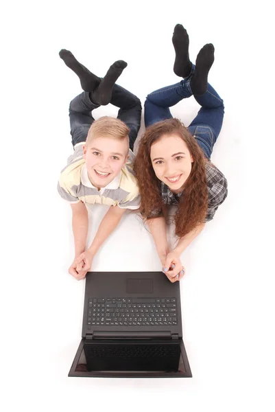 Boy and girl using a laptop lying on the floor — Stock Photo, Image