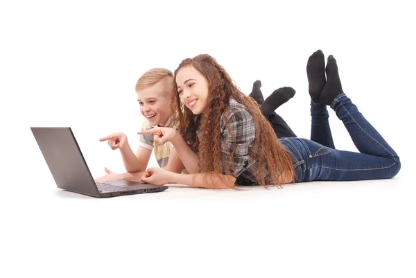 Boy and girl using a laptop lying on the floor — Stock Photo, Image