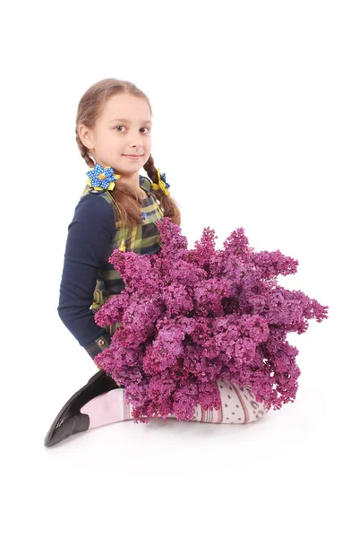 Jolie fille assise sur le sol blanc avec lilas à la main — Photo