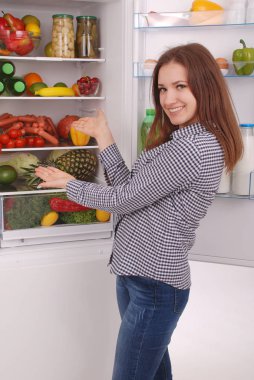 Dolgulu buzdolabı yakınındaki memnun ev kadını.