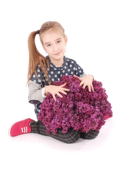 Chica atractiva sentada en el suelo blanco con lila en la mano — Foto de Stock