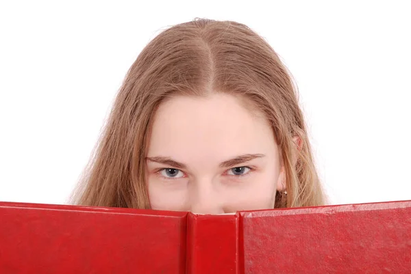 Beautiful school girl peeping from behind her red book — Stock Photo, Image
