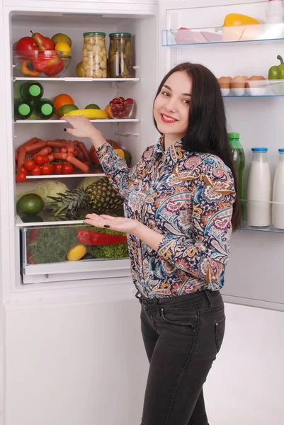 Довольная домохозяйка рядом с заполненным холодильником . — стоковое фото