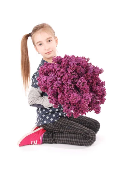 Attractive girl sitting on white floor with lilac in hand — Stock Photo, Image