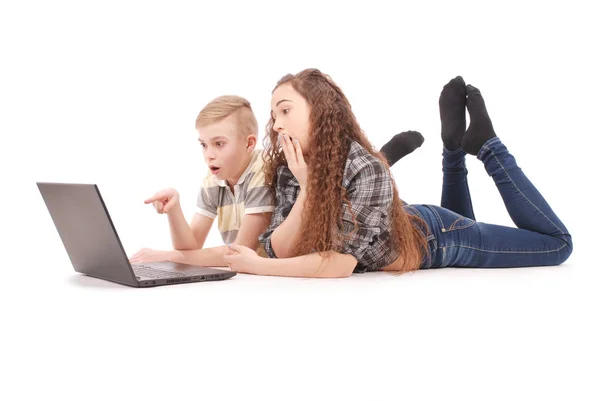 Boy and girl using a laptop lying on the floor — Stock Photo, Image