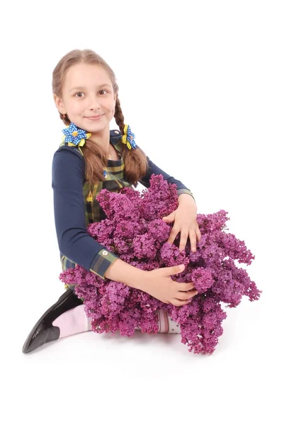 Jolie fille assise sur le sol blanc avec lilas à la main — Photo