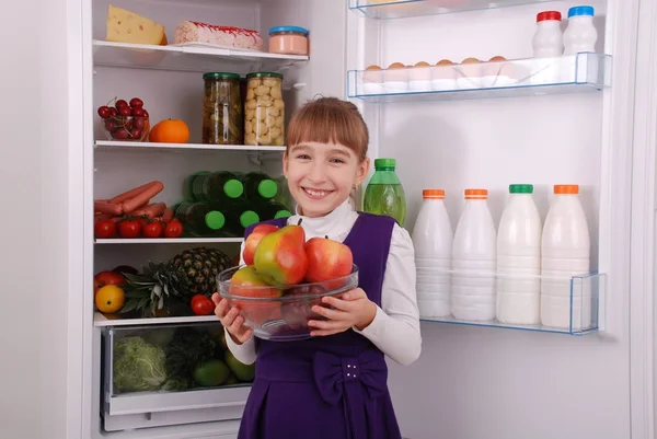 Mooi meisje in de buurt van de koelkast met gezonde voeding. — Stockfoto