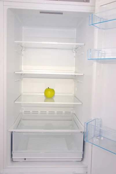 Jedno jablko v otevřené prázdné ledničce. — Stock fotografie