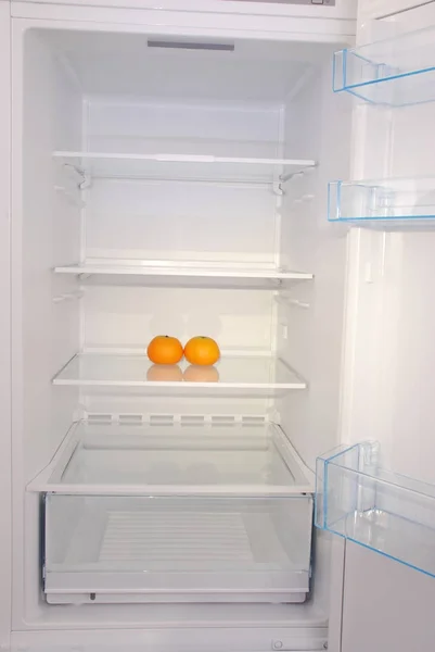 Dvě mandarinky v otevřených prázdná lednice. — Stock fotografie