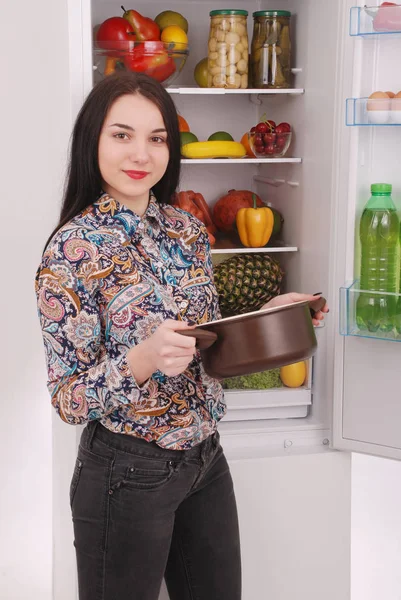 Satisfeito dona de casa perto da geladeira cheia . — Fotografia de Stock