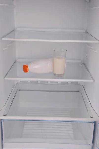 Copo de leite e garrafa no interior da geladeira limpa vazia — Fotografia de Stock