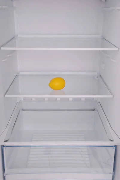 Ένα λεμόνι στο ανοιχτό άδειο ψυγείο. — Φωτογραφία Αρχείου