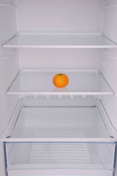 One mandarin in open empty refrigerator. — Stock Photo, Image