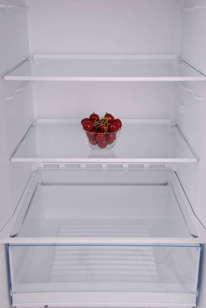 Cherries in open empty refrigerator.