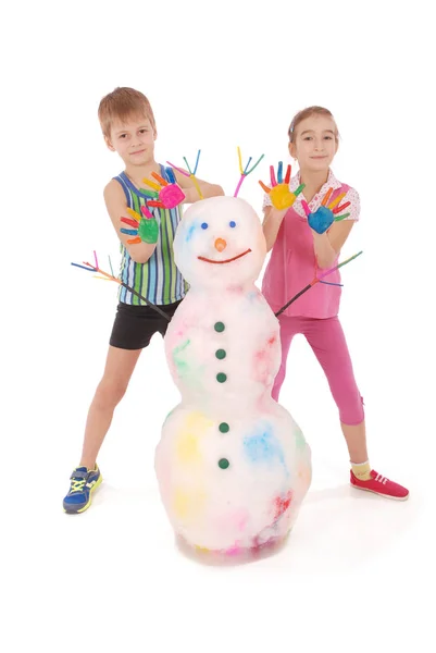 Beau garçon et fille avec les mains en peinture près de bonhomme de neige de couleur avec des cornes et des mains colorées — Photo