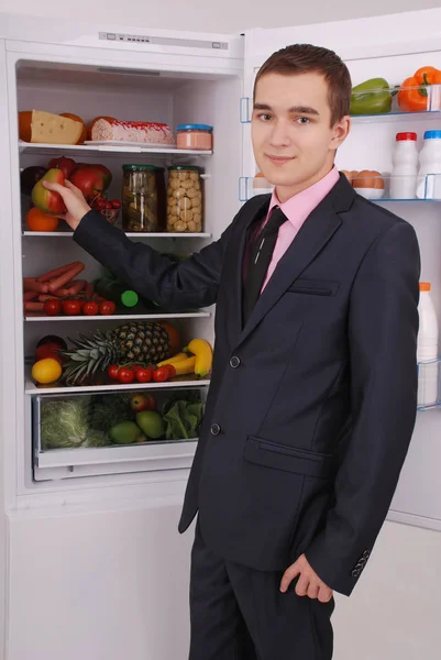 Tiener jongen in pak en stropdas in de buurt van de koelkast — Stockfoto
