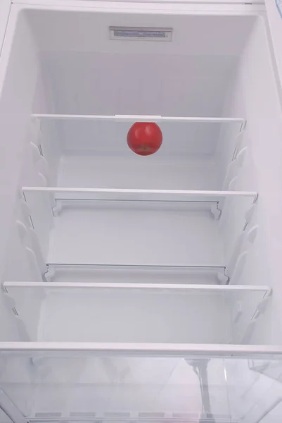 Una manzana en el refrigerador vacío abierto. — Foto de Stock