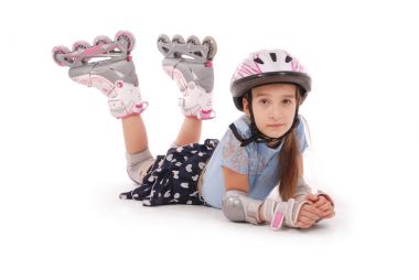 Mutlu küçük kız paten ve koruyucu giysiler yerde yatarken