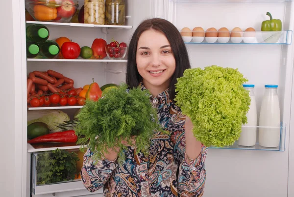 Mooi jong meisje in de buurt van de koelkast met gezonde voeding. — Stockfoto