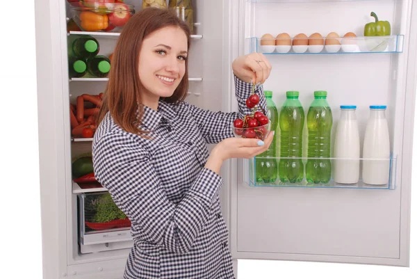 Beautiful young girl near the Fridge with healthy food.