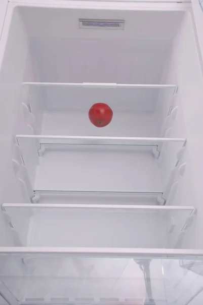 Una manzana en el refrigerador vacío abierto. — Foto de Stock