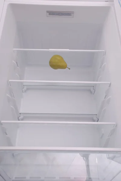 Una pera en el refrigerador vacío abierto . — Foto de Stock