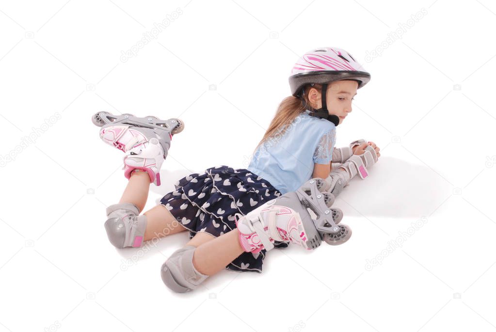 Happy little girl with roller skates and protective gear lying on the  floor