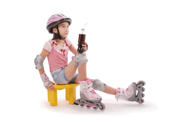 Charmantes braunhaariges Mädchen im Schulalter in kurzen Jeans-Shorts und rosa T-Shirt sitzt auf dem Stuhl und versucht, Rollschuhe zu Fuß zu gehen. — Stockfoto