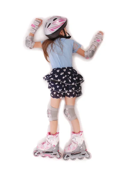 Happy little girl with roller skates and protective gear lying on the  floor — Stock Photo, Image