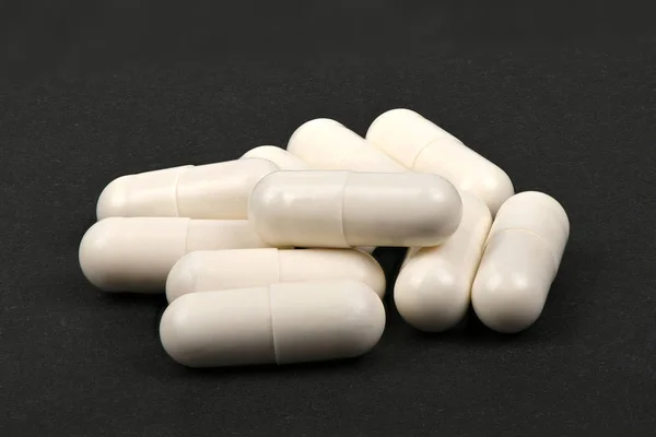 White pills on black — Stock Photo, Image
