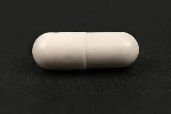 Witte pillen op zwart — Stockfoto