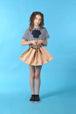 Mavi arka planda izole edilmiş bir paketolan çocuk. Tatil hediyesi, alışveriş. Alışveriş merkezinde çocuk mutlu alışveriş. 