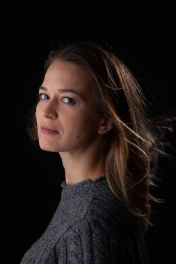 Siyah arka planda kameraya bakan bir kadın. Ön vesikalık