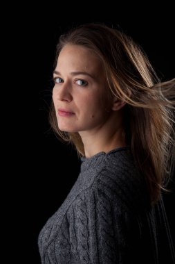 Siyah arka planda kameraya bakan bir kadın. Ön vesikalık