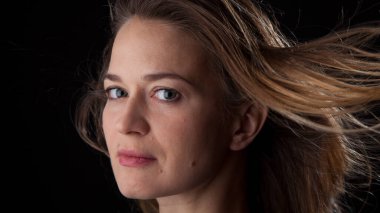 Siyah arka planda kameraya bakan bir kadın. Ön vesikalık