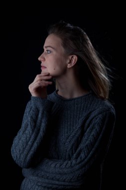 Siyah arka planda kameraya bakan bir kadın. Ön vesikalık