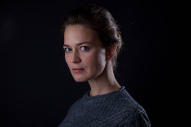 Siyah arka planda kameraya bakan bir kadın. Ön vesikalık