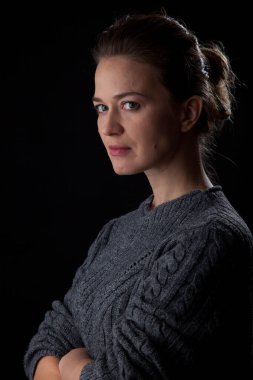 Siyah arka planda kameraya bakan bir kadın. Ön vesikalık. Kapalı duruş