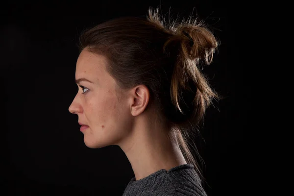 Woman on black background looking at camera. profile headshot