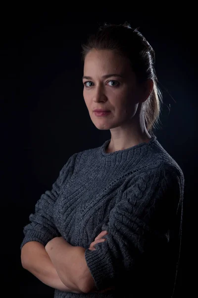 Woman on black background looking at camera. front headshot. Closed posture