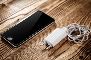 Ahşap arka plan üzerinde kablo telefon şarj cihazı