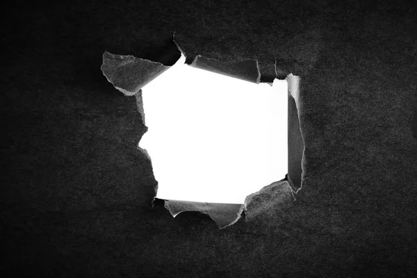 Hole in the black paper with torn sides — Stock Photo, Image