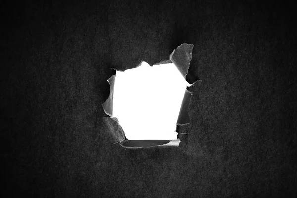 Hole in the black paper with torn sides — Stock Photo, Image