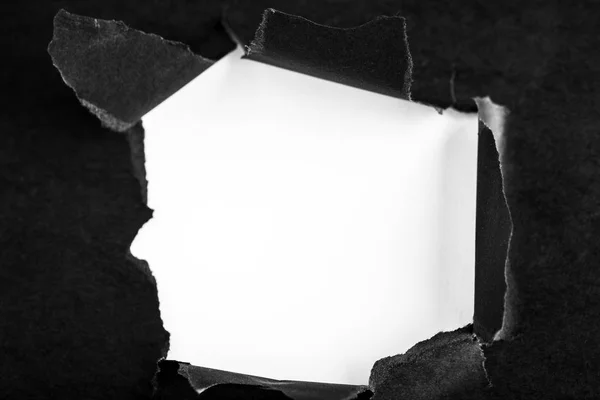 Loch im schwarzen Papier mit gerissenen Seiten — Stockfoto
