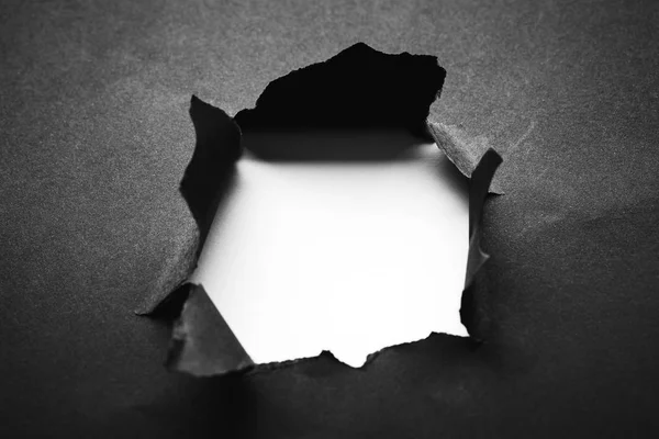 Hole in the black paper with torn sides — Stock Photo, Image