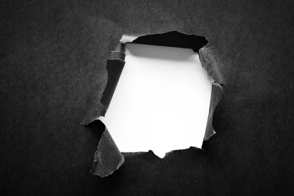 Hole in the black paper with torn sides