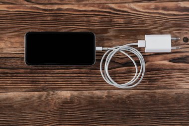 Ahşap arka planda kablo telefon şarj cihazları