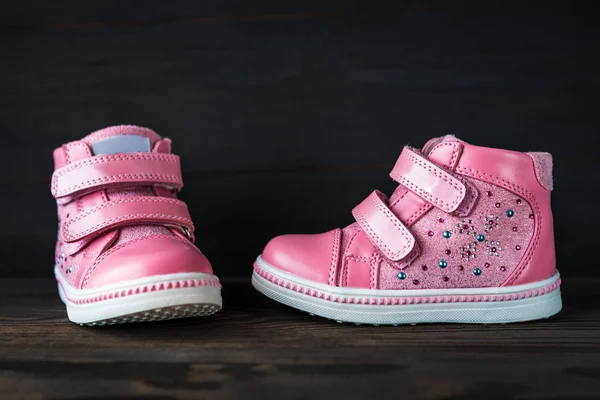 黑木背景下的粉红色儿童运动鞋 — 图库照片