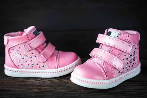 黑木背景下的粉红色儿童运动鞋 — 图库照片