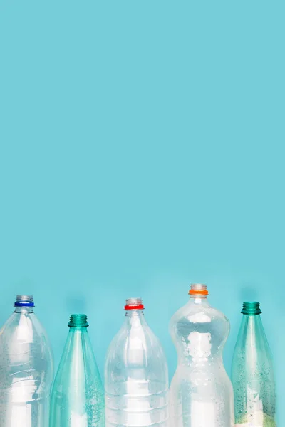 Zgniecione plastikowe butelki na niebieskim tle. Plastikowe śmieci. — Zdjęcie stockowe